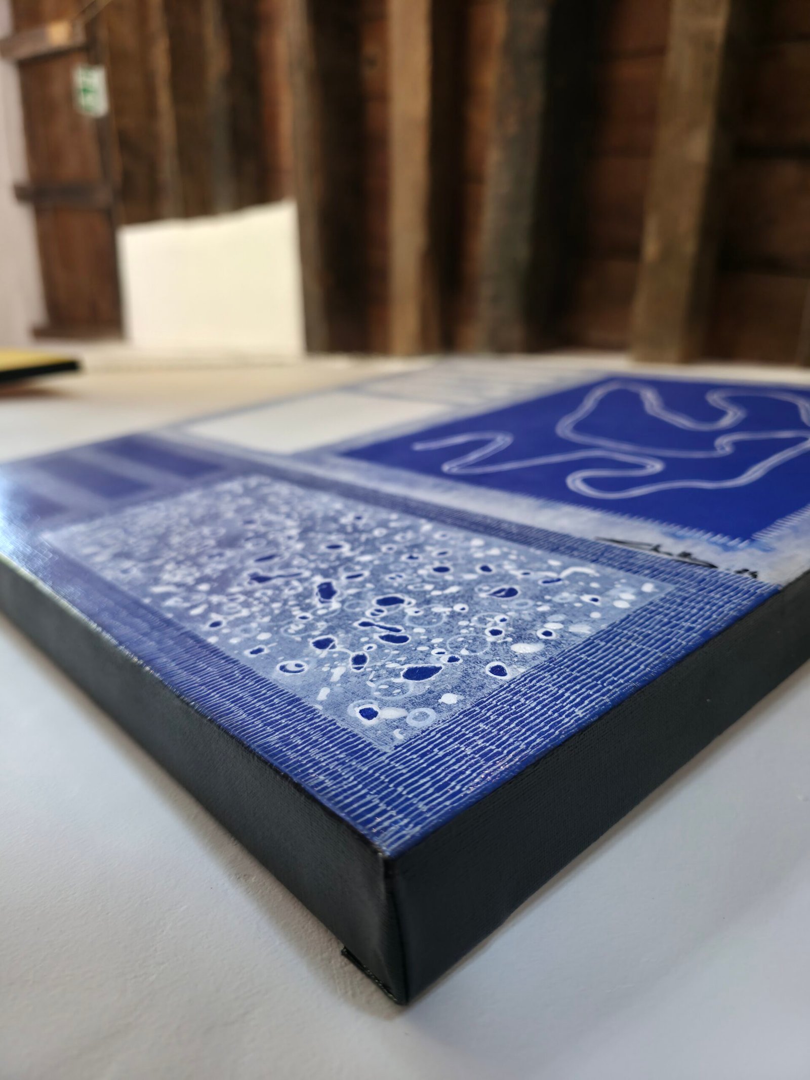 Détail macro de l'œuvre Marée intérieure par Chatti Karim. Peinture abstraite bleue aux textures craquelées et reliefs blancs. Collection L'Invisible, art contemporain français, travail de matière acrylique.