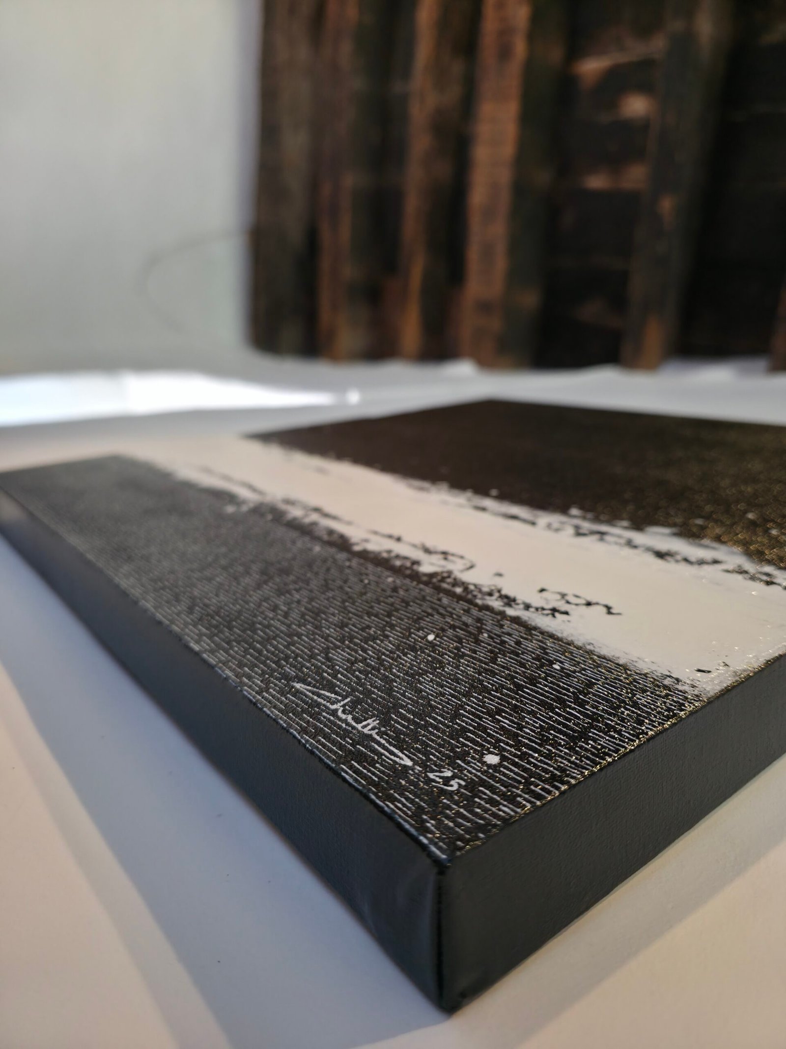Détail macro de l'œuvre Cœur de carbone par Chatti Karim. Vue latérale montrant l'épaisseur du châssis 3D (3,5 cm) peint en noir et la texture stratifiée de la peinture abstraite noir et blanc. Art contemporain français, collection L'Invisible.
