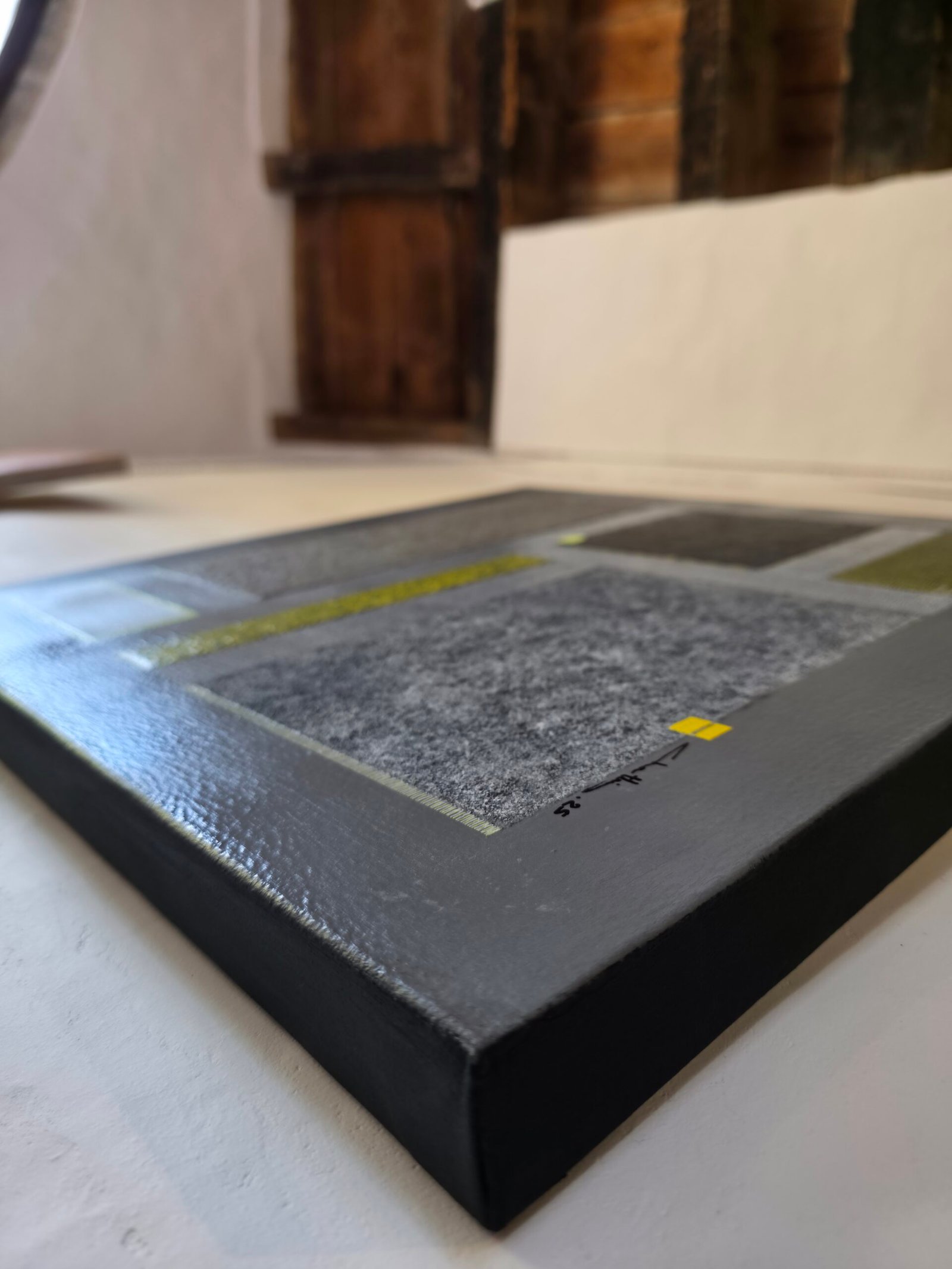 Vue de profil de Rempart des Murmures par Chatti Karim. Peinture abstraite contemporaine 50x50cm, collection L'Invisible. Détail de l'épaisseur du châssis 3D (3,5 cm) et de la texture acrylique avec sable et craquelures. Art contemporain français.
